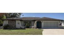 Charming single-story home featuring a stone accent wall, arched entryway, and well-manicured lawn at 21363 Cottonwood Ave, Port Charlotte, FL 33952