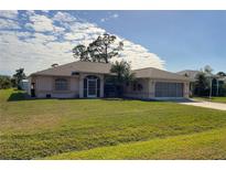 Charming single-story home with a well-maintained lawn and mature landscaping at 23395 Mullins Ave, Port Charlotte, FL 33954