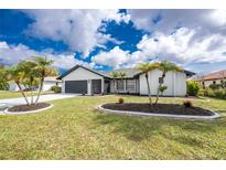 Well-manicured lawn with palm trees and black mulch flower beds enhances the curb appeal of this home at 25853 Aysen Dr, Punta Gorda, FL 33983