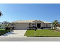 Well-maintained single-story home featuring a metal roof, green lawn, and an attached two-car garage at 379 Bal Harbor Blvd, Punta Gorda, FL 33950