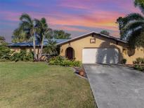 Charming single-story home featuring a lush landscaped yard with swaying palm trees and an inviting front entrance at 4114 Kinney St, Port Charlotte, FL 33948