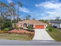 Charming one story home with an orange garage door and decorative landscaping at 15090 Buswell Ave, Port Charlotte, FL 33953