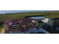 Aerial view of a red and yellow three-story apartment building with a white two-story house on a waterfront property at 17495 Boca Vista Rd # 6, Punta Gorda, FL 33955