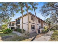 Exterior view of a two-story condo with palm trees and manicured landscaping at 19505 Quesada Ave # Ss102, Port Charlotte, FL 33948