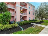 Exterior shot of a pink condo building with stairs and tidy landscaping at 2040 Willow Hammock Cir # 208, Punta Gorda, FL 33983