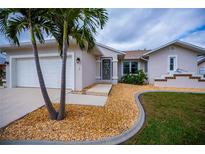 Charming home entrance featuring decorative door, rock landscaping, and a well-manicured lawn at 240 Riviera Ct, Punta Gorda, FL 33950