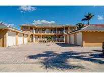Exterior view of multi-Gathering building with six garage doors, balconies, and brick paved parking lot at 3216 Purple Martin Dr # 121, Punta Gorda, FL 33950