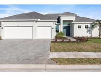 Beautiful single-story home with a three-car garage and gray brick driveway at 8604 Shore Lake Dr, Englewood, FL 34224