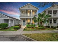 Charming two-story home features a welcoming porch, blue door, and beautifully landscaped front yard at 12492 Shimmering Oak Cir, Venice, FL 34293
