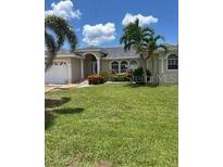 Charming single-story home with well-maintained lawn, arched entryway, and beautiful landscaping at 1303 Casey Key Dr, Punta Gorda, FL 33950