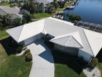 Stunning aerial view of waterfront home featuring a pristine white tile roof, lush landscaping, and private boat dock at 1407 Waxwing Ct, Punta Gorda, FL 33950