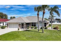 Charming single-story home featuring a well-manicured lawn, palm trees, and an attached two-car garage at 1434 Olancha Ct, Punta Gorda, FL 33983