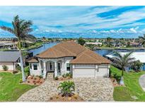 Beautiful waterfront home featuring manicured landscaping, brick driveway, and tile roof at 1492 Aqui Esta Dr, Punta Gorda, FL 33950