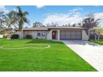 Charming single-story home featuring lush green lawn, palm tree, and a two-car garage at 22285 Walton Ave, Port Charlotte, FL 33952