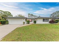Charming single-story home featuring a well-maintained lawn, paved walkway and two-car garage at 1052 Hinton St, Port Charlotte, FL 33952