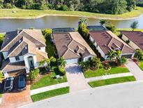 Beautiful waterfront homes featuring tile roofs, manicured lawns, and brick paver driveways at 12285 Canavese Ln, Venice, FL 34293