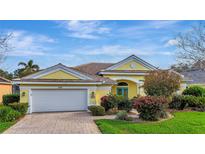 Charming one-story home with a yellow exterior, tile roof, a brick driveway, and meticulously maintained landscaping at 1616 Palmetto Palm Way, North Port, FL 34288