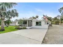 Quaint single-story home with manicured landscaping and a long concrete driveway at 23475 Harper Ave, Port Charlotte, FL 33980
