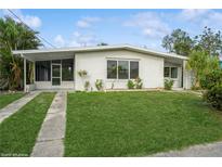 Charming single-story home with lush green lawn, palm trees, and a screened in carport at 3213 Normandy Dr, Port Charlotte, FL 33952