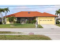 Charming single-story home featuring a well-manicured lawn, orange tile roof, and attached two car garage at 611 Bal Harbor Blvd, Punta Gorda, FL 33950