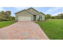 Charming single-story home with a brick driveway, manicured lawn, and attached garage at 616 Posadas Cir, Punta Gorda, FL 33983