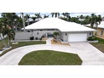 Inviting single-story home featuring a circular driveway, well-manicured lawn, and arched entryway at 931 Bal Harbor Blvd, Punta Gorda, FL 33950