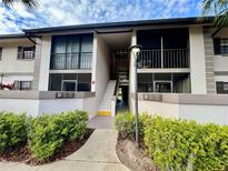 Condo exterior showing the units above on the second floor with screened balconies and stairs in the center at 1515 Forrest Nelson Blvd # R201, Port Charlotte, FL 33952