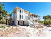 Charming coastal home featuring a screened porch and white lattice accents, creating a relaxing outdoor living space at 20 Palm Dr, Placida, FL 33946