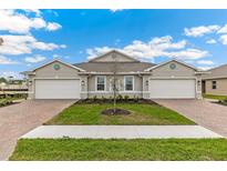 Beautiful exterior view of a modern, two-story home with a manicured lawn and brick paver driveway at 16408 Bridle Ridge St, Port Charlotte, FL 33953