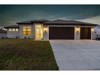 Charming single-story home featuring a spacious three-car garage and well-manicured lawn, illuminated for evening appeal at 23218 Fawn Ave, Punta Gorda, FL 33980
