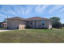 Charming single-story home with a well-maintained lawn and attached garage is bathed in sunlight under a blue sky at 30035 Alder Rd, Punta Gorda, FL 33982