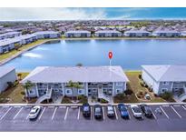 An aerial view of the condominium building with its manicured lawns, lakeside position, and ample parking at 3310 Loveland Blvd # 1808, Punta Gorda, FL 33980