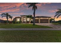 Beautiful single-Gathering home with a well-manicured lawn, palm trees, and a brick driveway at sunset at 3620 Carmichael Dr, Punta Gorda, FL 33950