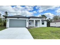 New construction home features a two-car garage, freshly laid lawn and a concrete driveway at 4818 Kiska Rd, North Port, FL 34288
