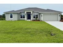Inviting single-story home featuring a well-manicured lawn and a two-car garage at 9171 Waldrep St, Port Charlotte, FL 33981