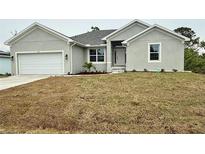 Charming single-story home featuring a two-car garage, manicured landscaping, and a welcoming front porch at 9590 Little Rock St, Port Charlotte, FL 33981