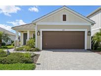 Charming single-story home featuring a brick driveway, well-maintained landscaping, and a tan-colored exterior at 10112 Canaveral Cir, Sarasota, FL 34241