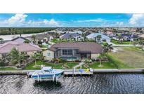Stunning backyard view featuring a pool, dock, boat, and screened-in lanai with lovely landscaping at 1336 Casey Key Dr, Punta Gorda, FL 33950