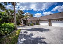 Spacious driveway leads to a charming home with an attached garage and lush, tropical landscaping at 1355 Red Oak Ln, Port Charlotte, FL 33948