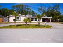 Charming single-story home with a carport, lush landscaping, and mature palm trees at 2521 Clipper Ship Way, Sarasota, FL 34231