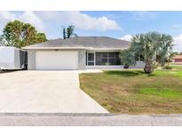 Charming single-story home featuring a well-manicured lawn, screened lanai and a two car garage at 3101 Brooklyn Ave, Port Charlotte, FL 33952