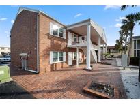 Two-story brick exterior with white trim, staircase and red brick entryway and courtyard at 380 Base E Ave # 202, Venice, FL 34285
