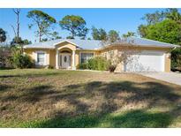 Inviting single-story home with a well-maintained front lawn and charming architectural details at 6938 Rabbit Ave, North Port, FL 34291