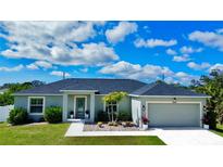 Charming single-story home with manicured lawn, gray stucco, and a two-car garage at 7243 Patricia Pl, Englewood, FL 34224