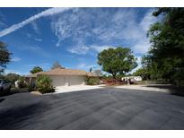 Charming single-story home with a spacious driveway, two-car garage, and a wooden deck, set against a clear blue sky at 825 Robinhood Dr, Punta Gorda, FL 33982