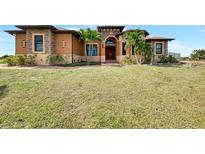 Stunning single-story home featuring lush lawn, front palms, and a warm, inviting entrance at 10393 Harlingen St, Port Charlotte, FL 33981