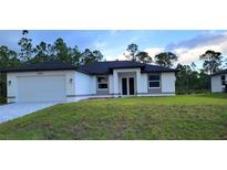 Beautiful single-story home featuring a two-car garage and well-maintained lawn at 23490 Macbeth Ct, Punta Gorda, FL 33980