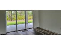 Bright living room featuring sliding glass doors, wood-look flooring, and neutral paint at 23490 Macbeth Ct, Punta Gorda, FL 33980