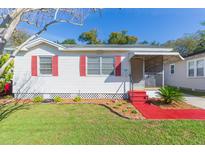 Charming single-story home with red shutters, a well-manicured lawn, and vibrant red steps at 305 W South Ave, Tampa, FL 33603