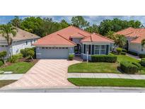 Charming single-story home featuring a red tile roof, paver driveway, attached garage, and well-manicured landscaping at 5017 Hanging Moss Ln, Sarasota, FL 34238